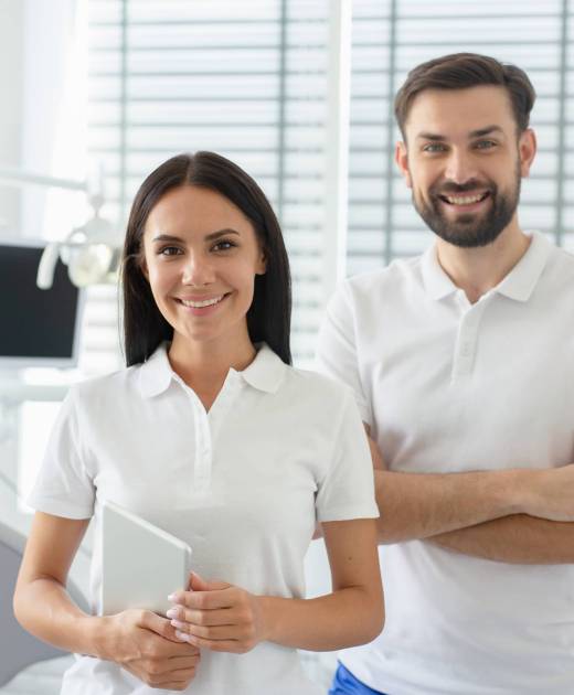 portrait of young male and female dentists looking at camera in dental office