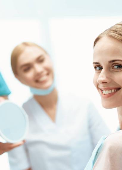 A woman is sitting in a dental office in a dental chair.